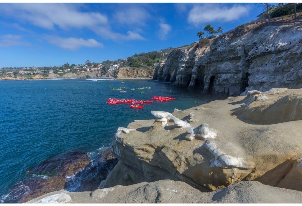 Coastline of La Jolla with Caves on the right and 2 groups with kayakers in the ocean on the left - Kayaking in La Jolla