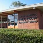 The corner of a brick building with metal letters that say city of san diego public library clairmont branch
