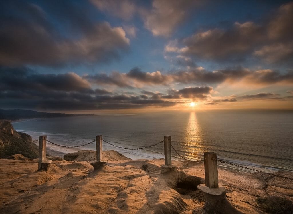 Sandstone cliff with security chain on a cliff at Torrey Pines La Jolla overlooking the Pacific Ocean at sunset