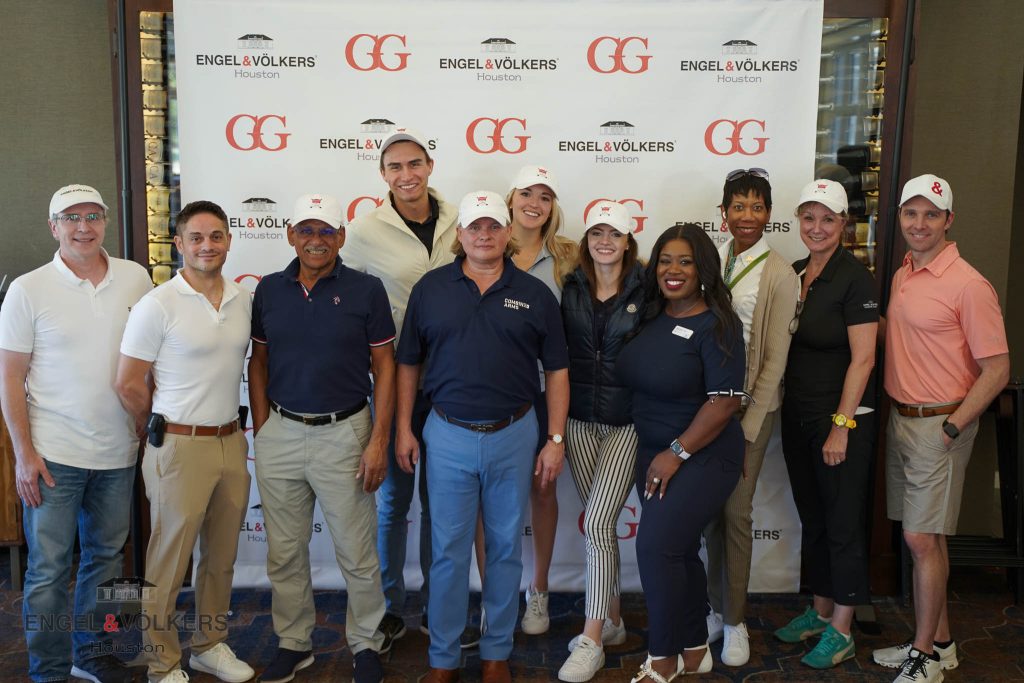 Engel & Völkers real estate advisors in front of a branded step-and-repeat during a golf charity event.