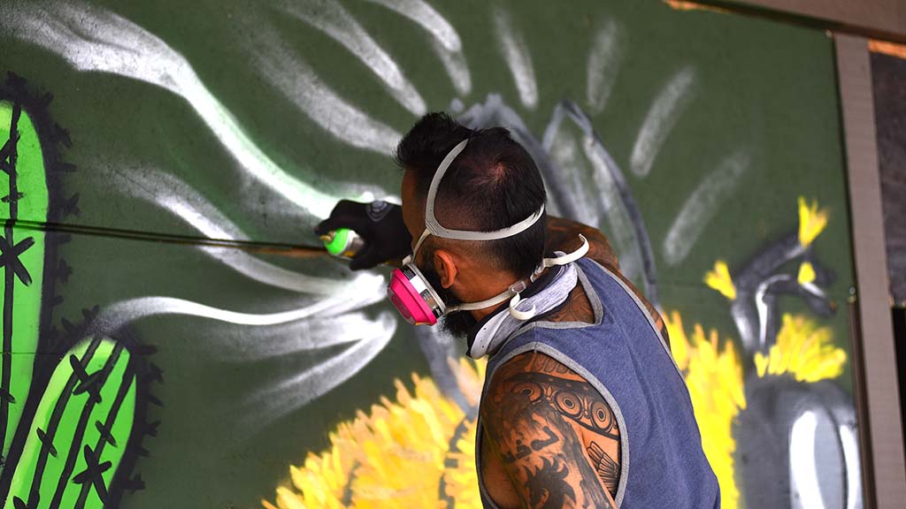Artist Lourans Mikhail paints a mural with a bee to help beautify the La Mesa Shopping Center after business were looted and windows were smashed.