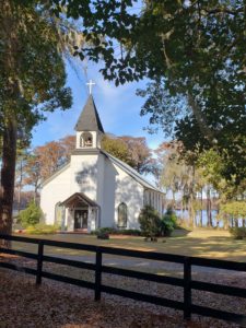 Beautiful little white church, with antique stained glass windows, in front of a lake