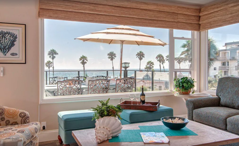 Cozy living room with large windows overlooking outdoor patio and ocean views.