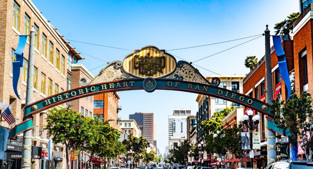 Sign of the Gaslamp Quarter with palm trees and tall buildings in background on sunny day. Gaslamp District, Downtown San Diego. San Diego Coaster.