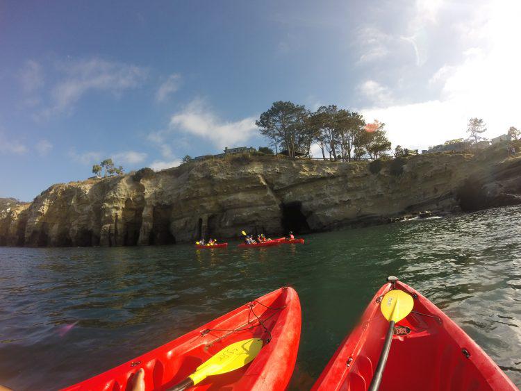 tip of two red kayaks in the forground and the la jolla caves in the background