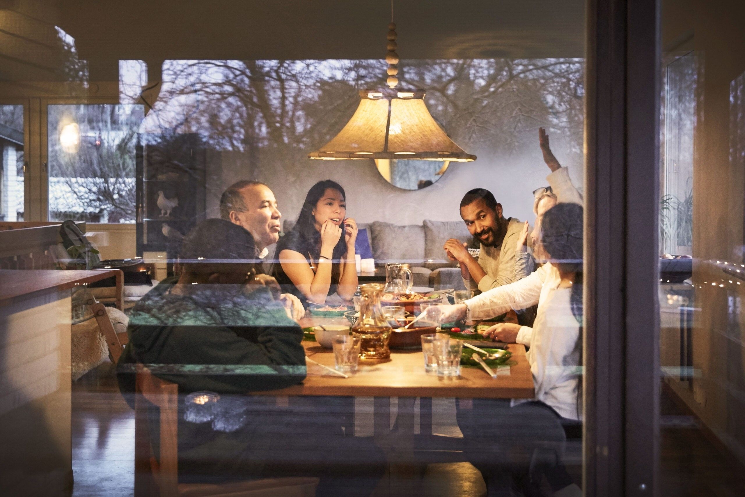 a multigenerational family laughing together over dinner at home