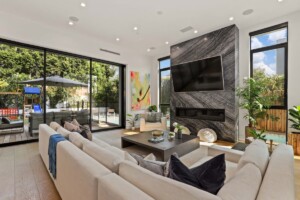 sleek contemporary living room with large windows and marble fireplace