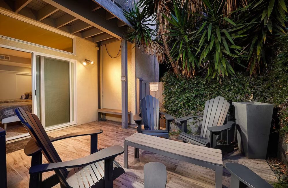 Small outdoor courtyard with Adirondack chairs and patio furniture surrounded by lush greenery. Downtown San Diego home. San Diego vacation homes.