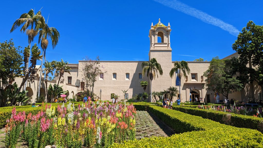 Alcazar Garden Balboa Park with colorful flower beds in the foreground, moorish architecture building with tower in the background