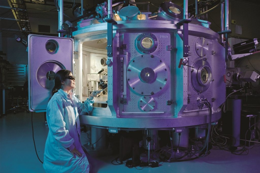 Woman reaching into a scientific chamber that is light mystically from the inside