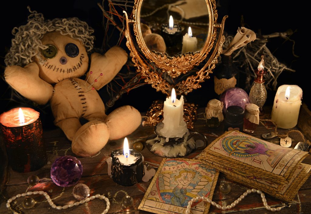 Magic ritual with voodoo doll, mirror, candles and tarot cards. Halloween concept, mystic or divination spell with occult and esoteric symbols. Vintage objects on witch table