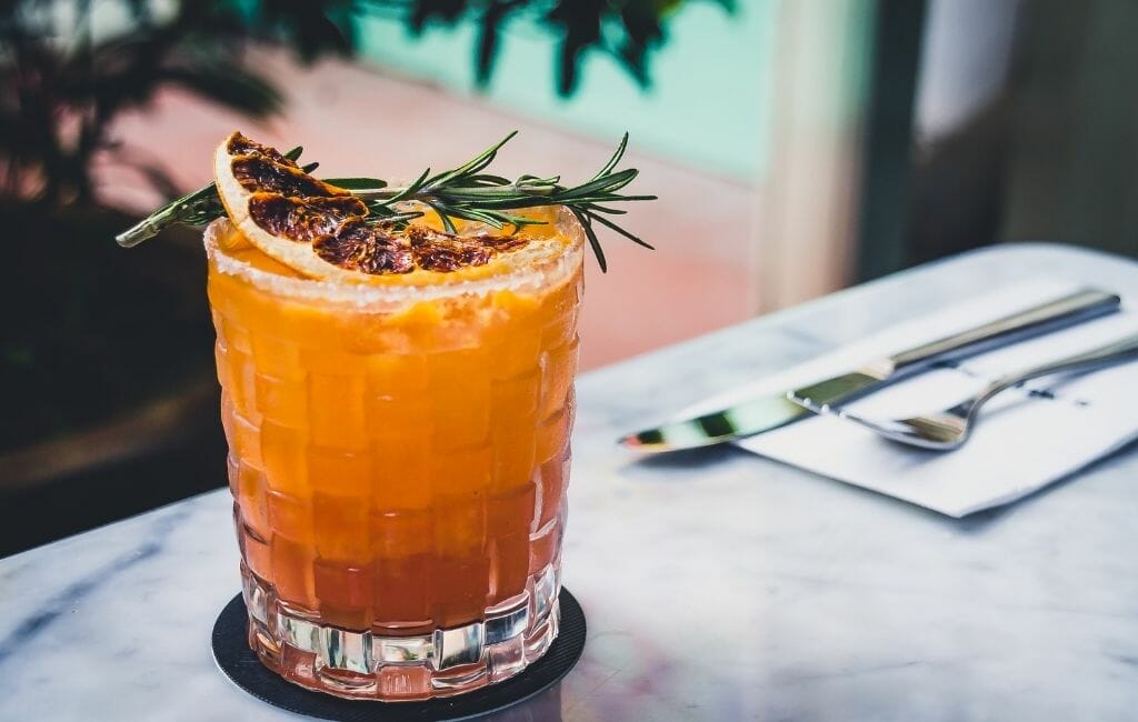 Mexican Mezcal coctail in a glass with rosemary and blood orange