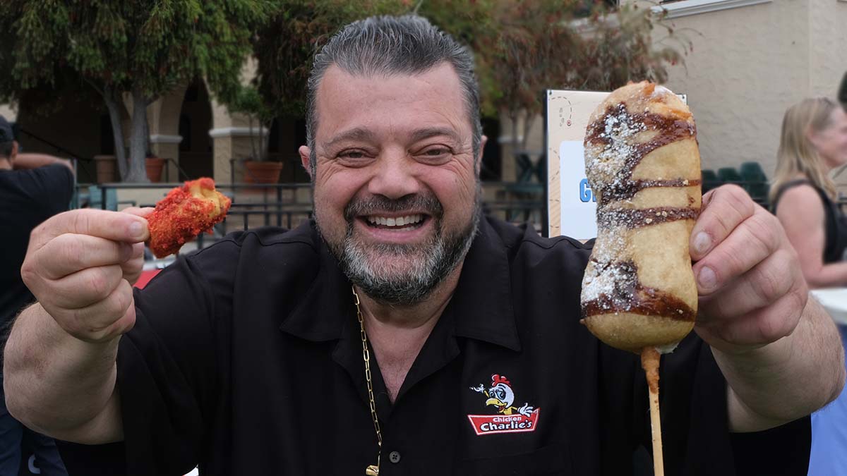 Charlie Boghosian, owner of Chicken Charlie's, holds this year's new items: Flaming Hot Cheetos Potstickers and deep fried s'mores on a stick. Photo by Chris Stone