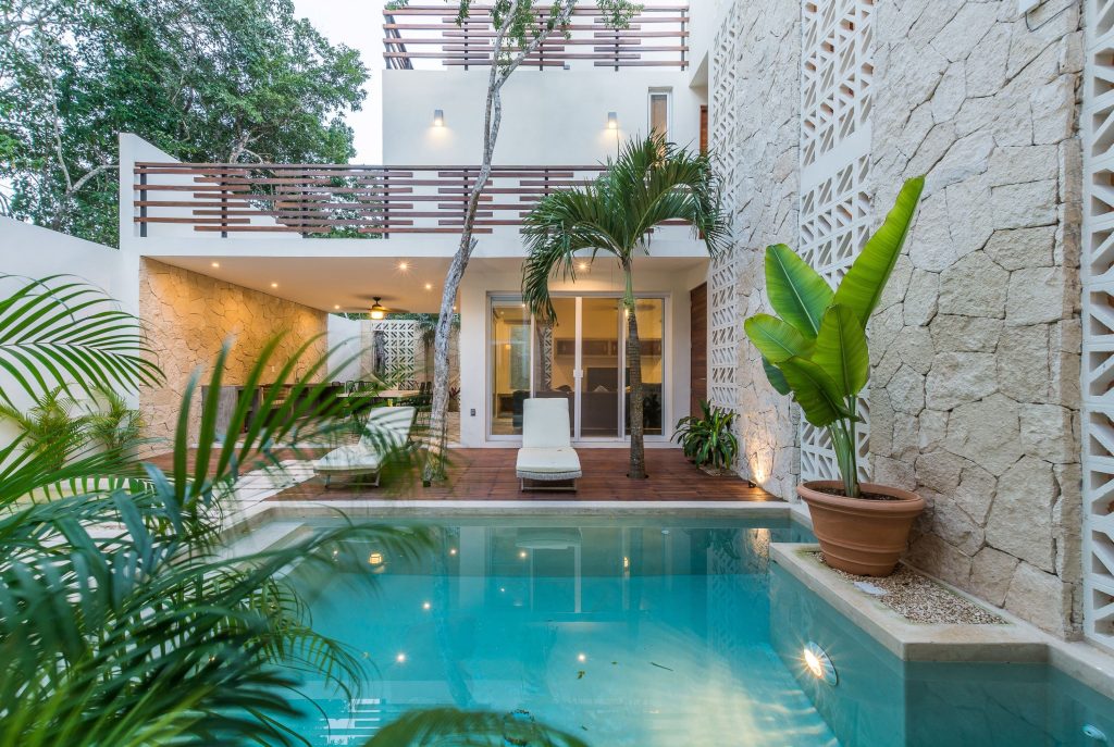 The exterior of a luxury home in Tulum, with outdoor seating and a luxurious pool.