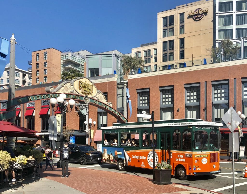 Entrance to Historic Gaslamp Quarter with red historic trolley city tour bus in the foreground and the San Diego Hard Rock Hotel in the background