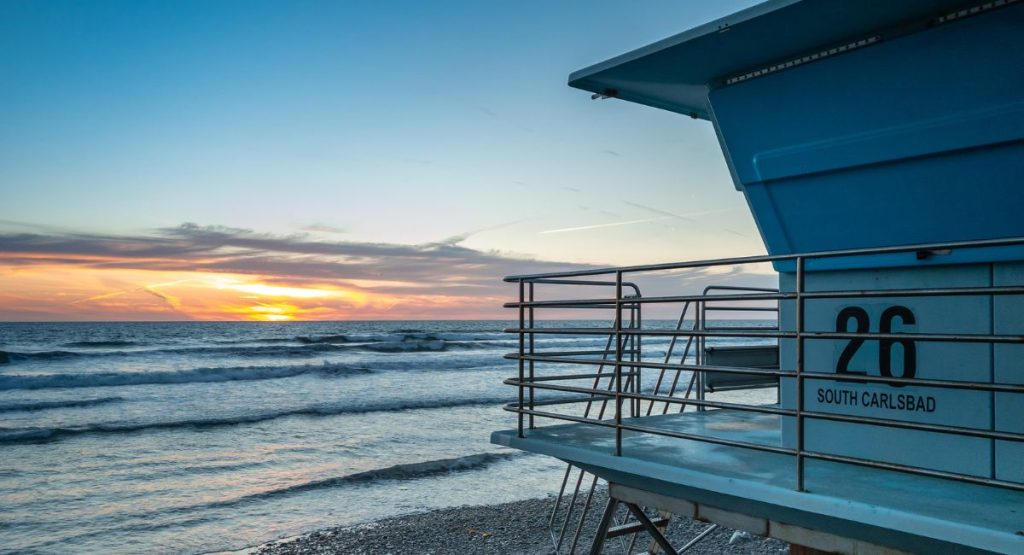 Beach lifeguard stand overlooking Pacific Ocean and colorful sunset. Carlsbad State Beach. Places to visit in Carlsbad.