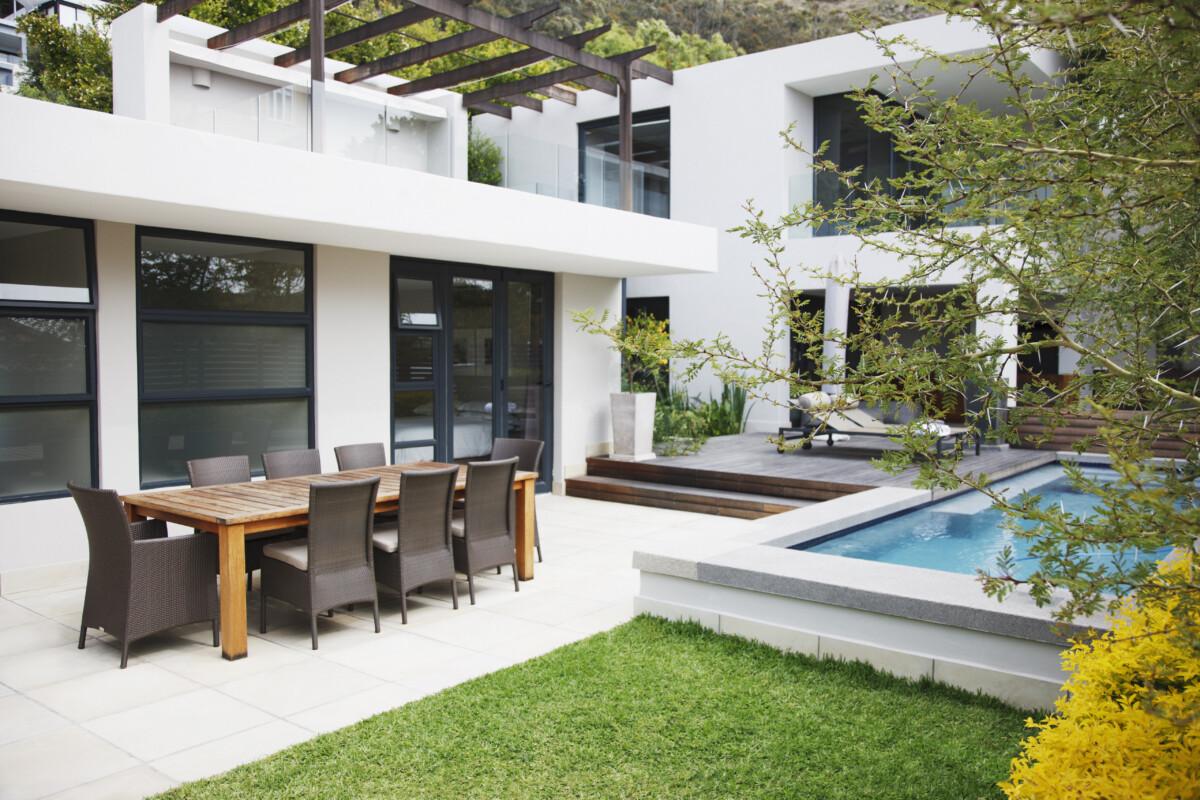 Dining area next to modern house and swimming pool