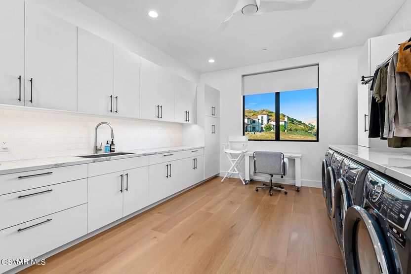 Laundry room with sink and multiple washers and dryers