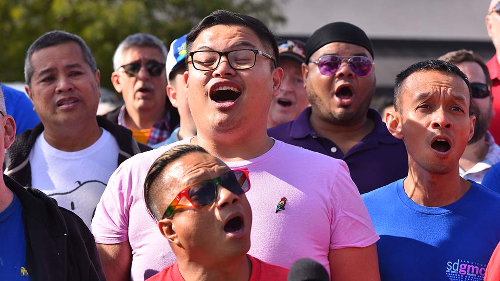 Members of the San Diego Gay Men's Chorus sings "Somewhere Over the Rainbow" near the rainbow crosswork on Normal Street and University Avenue.