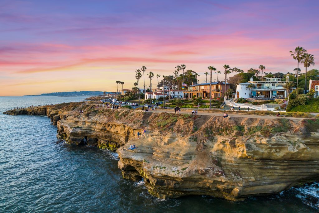 Luxury homes on rocky Californian cliffs at sunset.