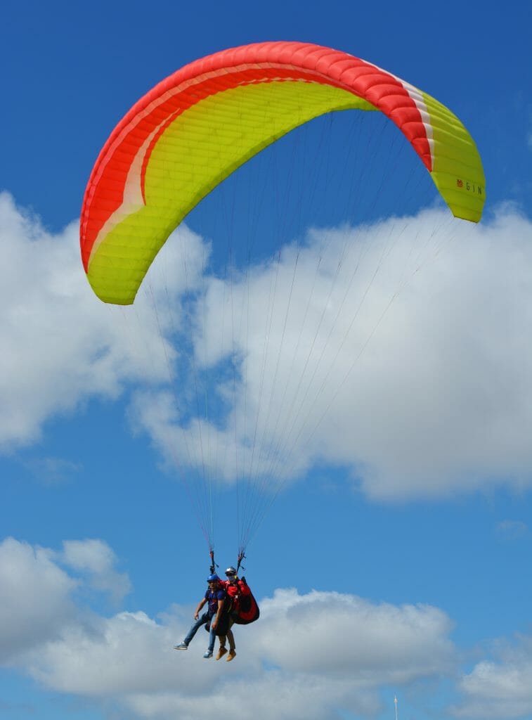 Double Paraglider with orange/yellow parachute in Torrey Pines