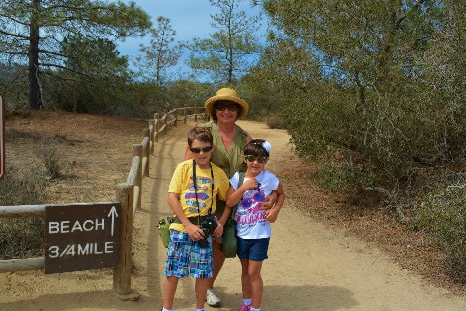 Woman hugging her two grandchildren on the hiking trail at Torrey Pines, San Diego