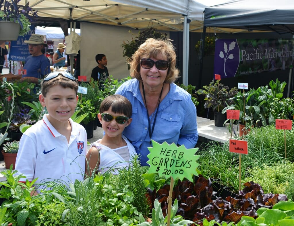 Woman in blue shirt with two young children at the farmers market