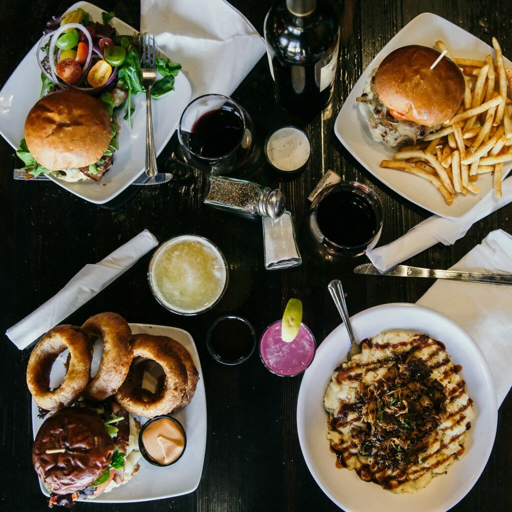 flatlay table shot with 4 main plates and drinks on a dark table