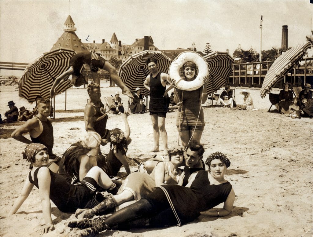 historic picture in sepia with ladies in the 20s in swimsuits on the beach at the hotel del coronado