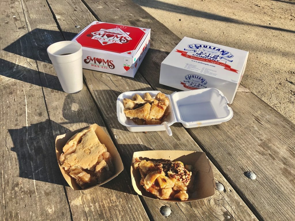 A selection of apple pie slices and pie boxes on a wood table - Julian Apple Pie Taste Testing