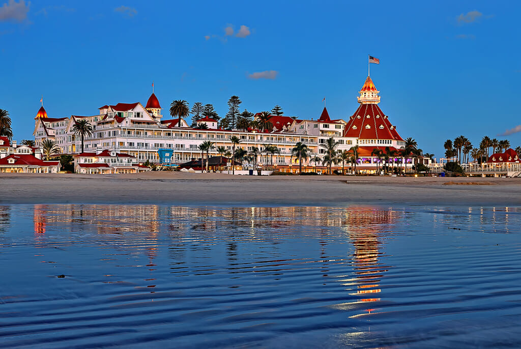 view of hotel del coronado from the water - historic white victorian building with red roof.