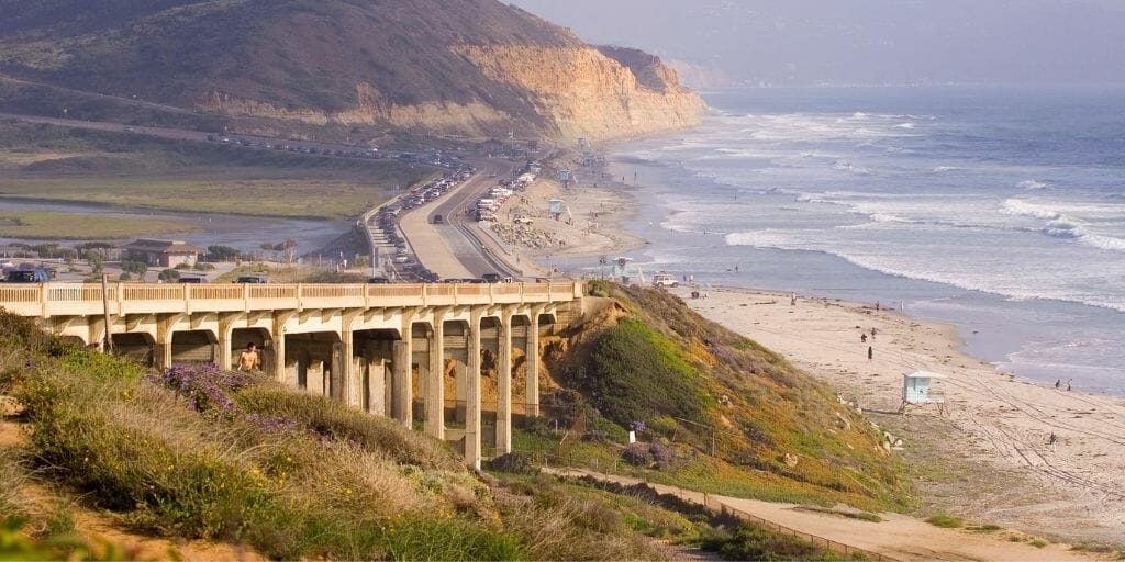 Aerial view over Southern California Beach with a bridge in the foreground, the beach to the right, and Torrey Pines Cliffs in the background