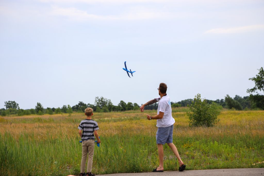 Father and son flying a toy airplane in beautiful field. 