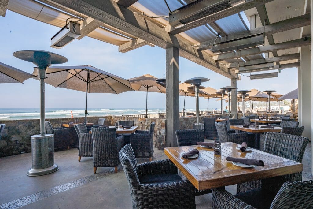 outdoor patio with with white umbrellas and heaters overlooking the beach at Pacific Coast Grill