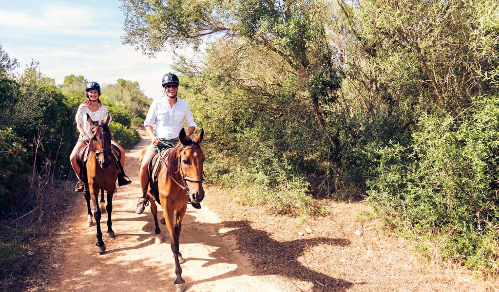 Man and woman riding on horses on a trail 