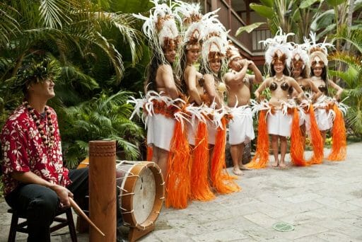 Performance of Polynesian dancers in orange palm skirts and white feather headdresses
