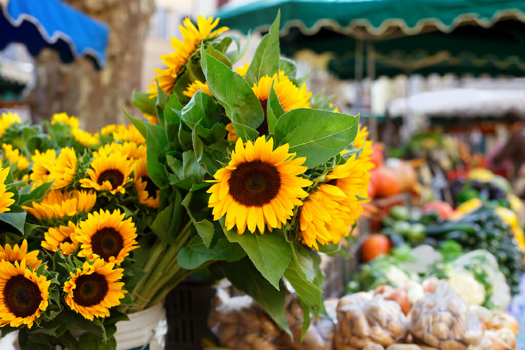 Farmers market with vegetables and sunflowers.