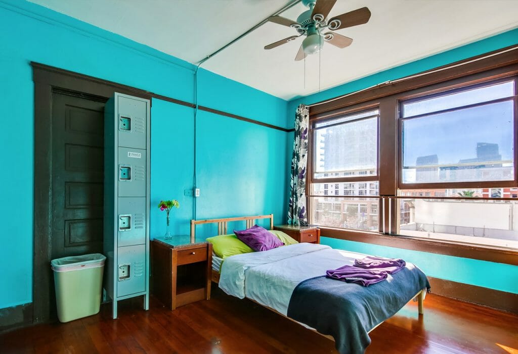Room at Hostel in San Diego - Bright turquoise walls and two large windows looking out at downtown