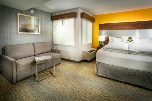 Room at Hotel Z in San Diego with bed, couch, corner windows and bright yellow accent wall