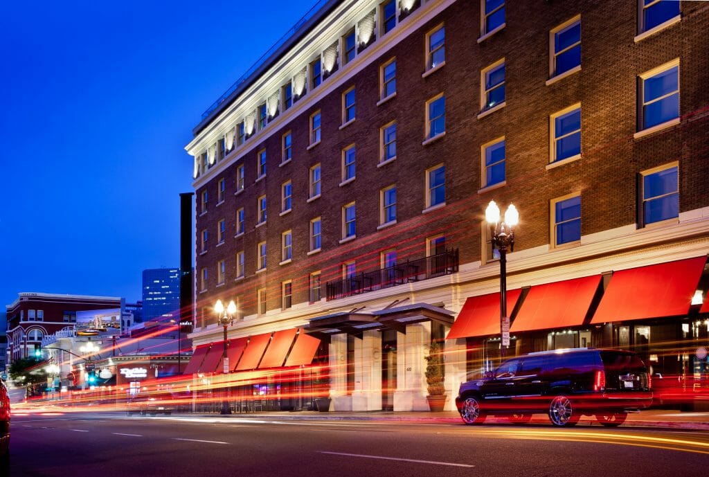 Long exposure photo of Andaz hotel during blue hour. Brick building with white trim and red sun shades on the first floor