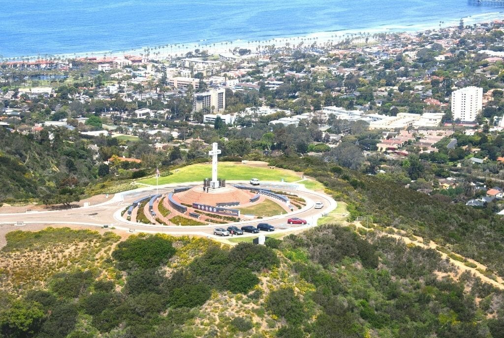 Aerial view fo white cross on top of Mt Soledad National Veterans Memorial San Diego with the ocean and the houses of La Jolla in the background
