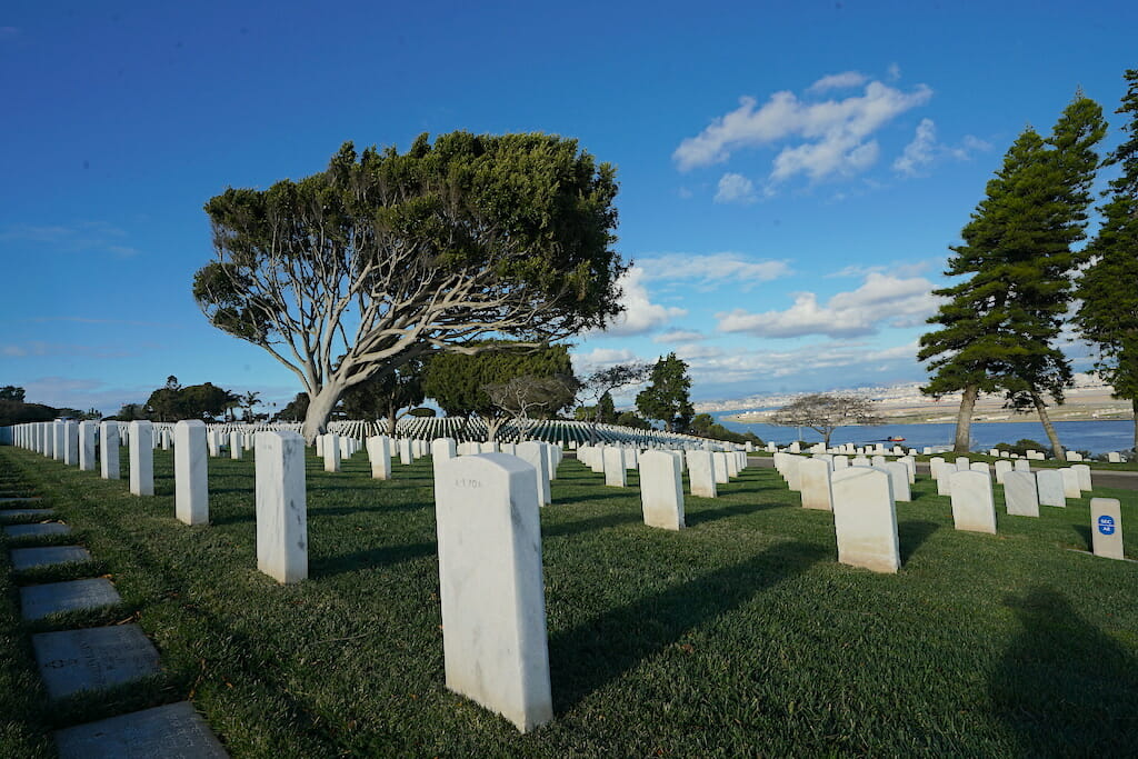 Rows of White grave stones on a sloping meadow overlooking San Diego Bay and Coronado from Fort Rosecrans Cemetary San Diego