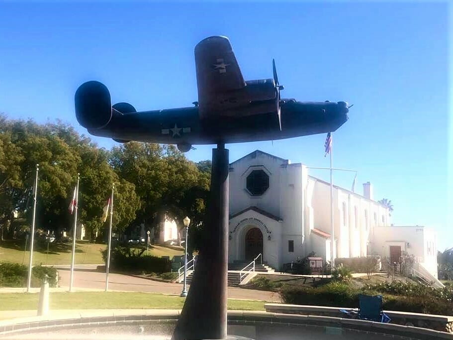 Old propeller plane statue in front of a white church at the Veterans Museum and Memorial in San Diego