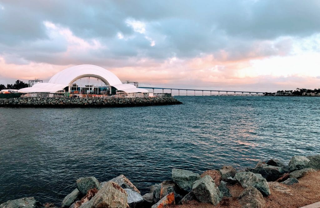 White shell-shaped concert hall on the embarcadero in San Diego Bay with the Coronado Bay Bridge in the Background - The Rady Shell Symphony San Diego