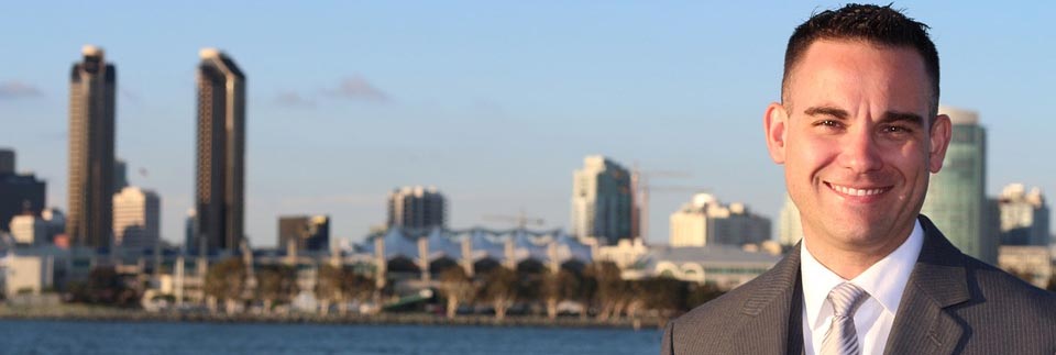 Male with a suit on. Tie. Water scene. City in the background. Buildings. Skyscrapers.