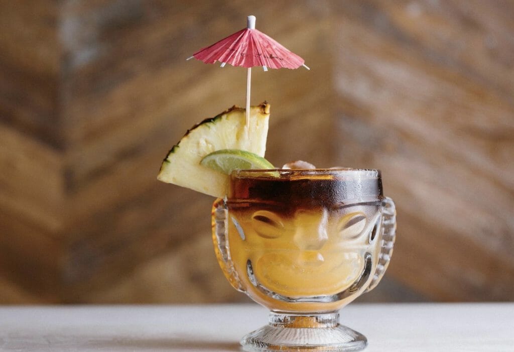 Mai Tai cocktail in a Tiki-inspired glass with slice of pineapple and pink umbrella