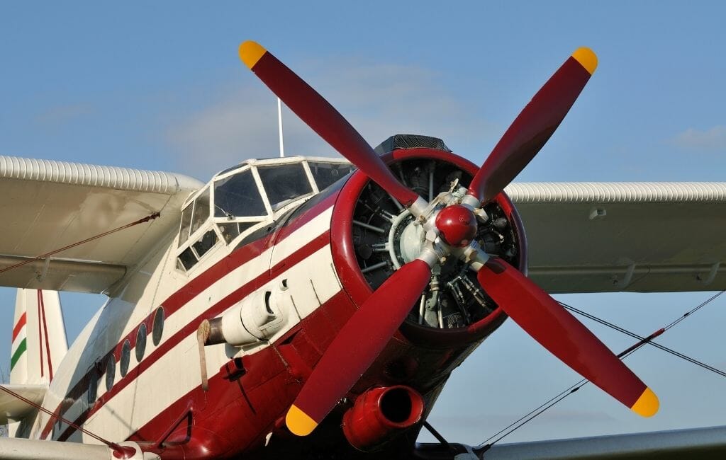 red and white biplane with propellor