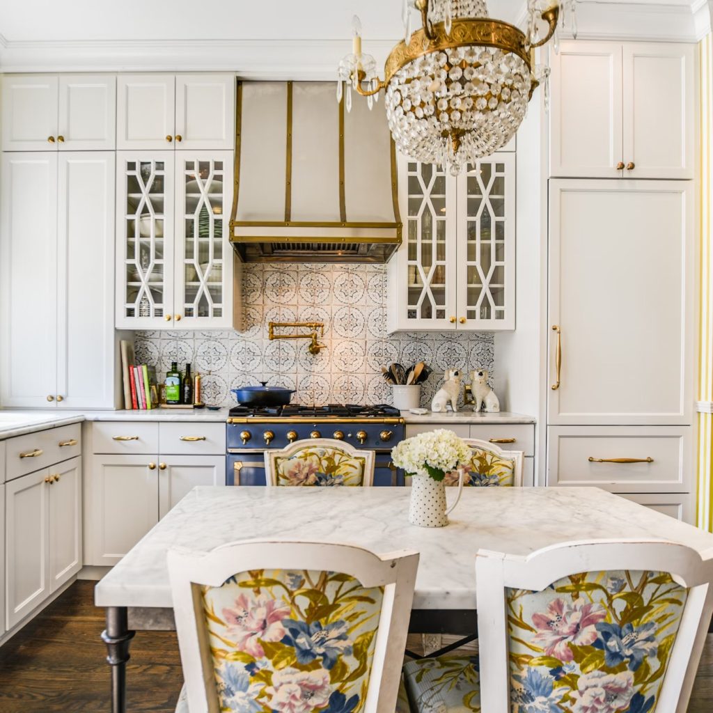 Chic, luxurious kitchen with unique blue stove and floral-design chairs.