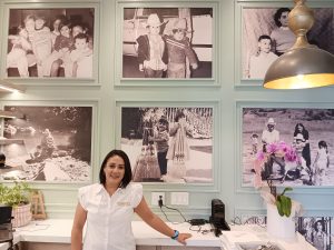 paulina chaidez, co owner of cocina 35 brunch in liberty station, standing next to a wall mural of family photos.