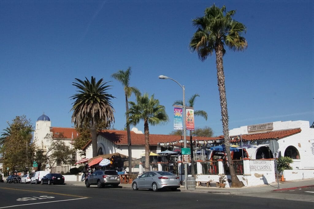 On a clear day, pedestrians walk around Old Town San Diego and its mexican style buildings